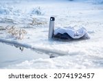 Small photo of Thermos, slippers and a towel near the ice hole. Winter swimming. Hot drink in winter. Get warm with coffee. Ice and snow.