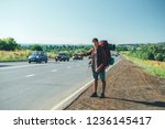 Travel man hitchhiking. Backpacker on road.