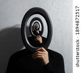Small photo of Enigmatic surrealistic optical illusion, young man holding round frame on textured grey background.