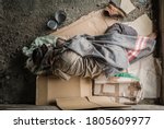Old homeless man wearing sweater and blanket sleeping on cardboard seeking help because hungry and food beggar from people walking pass on street. Poor man homeless and depression concept.