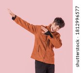 Small photo of Portrait of asian handsome young man in fashionable clothing and enjoy standing with gesture dab dance isolated on pink background.