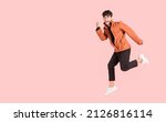 Small photo of Happy handsome Asian man in fashionable clothing and jumping doing winner gesture isolated on pink background. Portrait of young male cheerful confident and excited jump in air and smile in studio.