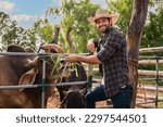 Portrait of happy handsome man cattle farmer owner standing looking at camera having cheerful on outdoors in organic cow farm. Confident male farmer worker smiling and grass feed to cow in livestock.