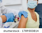 Small photo of Female doctor or nurse giving shot or vaccine to a patient's shoulder. Vaccination and prevention against flu or virus pandemic.