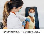 Female doctor or nurse giving shot or vaccine to a patient's shoulder. Vaccination and prevention against flu or virus pandemic. 