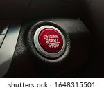 Engine start / stop button switch that has a red colour on a car console panel in a luxury car.