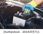Technician is pulling up an car old battery for replacement