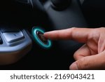 The driver palm as it presses the electric car engine start stop button with a green light illuminated