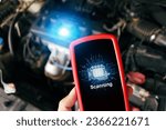 Car engine scanning with wireless technical tool, OBD2 scanner tool in a mechanic hand with a car engine compartment blurred on background, Car maintenance service concept