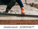 Selective focus, Construction worker leveling concrete floor with trowel. Construction worker pouring cement and concrete.