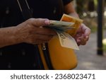 Small photo of A pensioner woman holds new Israeli shekel banknotes and an Israeli citizen passport in her hands. Concept pension, social assistance, budget, old-age benefits, new repatriate