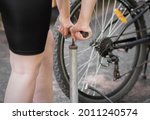 A girl pumps a bicycle wheel with a pump. Bicycle repair in the forest. Close up.