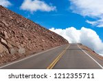 A mountain road climbs towards the clouds.
