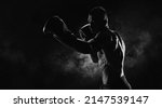 Small photo of Kickboxer in black gloves posing on a background of smoke. The concept of mixed martial arts.