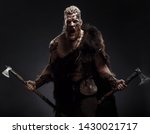 Small photo of Medieval warrior berserk Viking with tattoo with axes attacks enemy. Concept historical photo