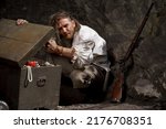 Small photo of Sea robber captain of pirate ship armed with treasure chest in cave. Concept historical halloween. Filibuster cosplay.