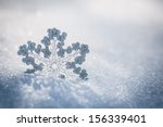Silver Christmas decoration. Beautiful snowflake on real snow outdoors. Winter holidays concept