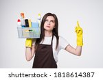 Young attractive smiling housewife wearing casual clothes, latex gloves holding full basin of cleaning agent, isolated on white