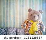 ิฺBig teddy bear in living room with pastel background patterns vintage wallpaper and cute pillow.
