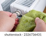 Bleed air valve in heating radiator. Adjust heating system, preparing the house for the new cold autumn or winter season. Hand with a key for draining air drains water and air from the heater.