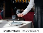 Small photo of A young waiter in a stylish uniform is engaged in serving the table in a beautiful gourmet restaurant close-up. Table service in the restaurant.