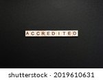 Small photo of Word accredited made up of wooden blocks on black cardboard background. Minimum concept of accreditation.