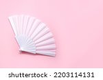 Small photo of White fan on pink background. Minimal concept of menopause and female hot flashes. Copy space, top view