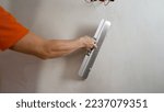 Small photo of Puttying the wall, close-up. Master's hands apply the finishing putty on the concrete wall, close-up.A man is plastering the wall with a spatula. Builder applies putty on the wall close up.