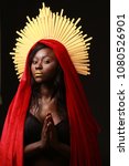 Small photo of Black skin woman dressed in a red clothes/ fabric with golden aureole, praying
