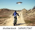A boy riding a bicycle following a UFO. I want to believe. Photo with 3d rendering element