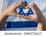 Small photo of Heartfelt Gesture. Child Forms a Heart with Hands, Framing Magen David On Israeli Flag - Love Israel, Unity, Jewish Identity, Patriotism Symbol.