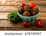 Small photo of Falafel balls in a bowl and fresh vegetables on a wooden background. Falafel is a traditional Middle Eastern food, commonly served in a pita. Falafel delivers pizazz, in color, texture, and taste.
