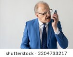 Portrait of stressed mature businessman shouting in mobile phone. Senior manager wearing formalwear and eyeglasses answering unpleasant call. Angry boss concept
