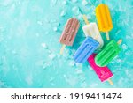 Selection of bright multicolored ice cream popsicle. Various gelato, frozen lollypops - chocolate vanilla blueberry strawberry pistachio orange, with crushed ice on light blue sunny background