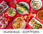 Small photo of Traditional Chinese lunar New Year dinner table, party invitation, menu background with pork, fried fish, chicken, rice balls, dumplings, fortune cookie, nian gao cake, noodles, chinese decorations
