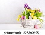 Easter greeting card background, banner format. Festive white basket with green grass, spring flowers bouquet, colorful Easter eggs, woman hands in picture take basket side view