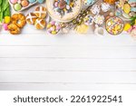 Small photo of Easter brunch, breakfast food, Kids Easter party buffet. Various traditional Easter sweets, candy, pasties and baking - cross buns, cheesecake, chocolate eggs, pancakes, cupcakes, top view copy space