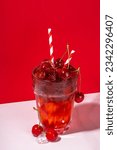 Small photo of Iced cherry cola drink, Cold summer fruity non-alcohol cocktail with fresh cherries, juice, cola and ice, on high-colored background copy space