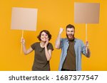 Small photo of Joyful protesting two people guy girl hold protest signs broadsheet blank placard on stick doing winner gesture isolated on yellow background. Protests strikes pickets concept. Youth against city