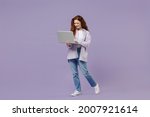 Full size body length cute young redhead curly green-eyed woman 20s wear white T-shirt violet jacket hold use work on laptop pc computer isolated on pastel purple color wall background studio portrait