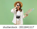 Traveler amazed exploring tourist woman in casual clothes hat hold paper map look through binoculars isolated on green background Passenger travel abroad weekends getaway Air flight journey concept.