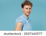 Small photo of Calm swanky young curly man 20s years old wears azure t-shirt having adhesive plaster at injection syringe of medicine drug virus vaccine isolated on plain pastel light blue background studio portrait