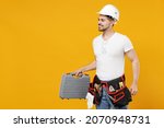 Young side view confident employee handyman man 20s in protective helmet hardhat tool case box walk isolated on yellow background Instruments accessories renovation apartment room Repair home concept
