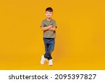 Full body little small smiling happy boy 6-7 years old wearing green t-shirt hod hands crossed folded look camera isolated on plain yellow background studio Mother