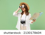Traveler smiling exploring tourist woman in casual clothes hat hold paper map look through binoculars isolated on green background Passenger travel abroad weekends getaway Air flight journey concept.
