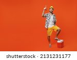 Young smiling happy fun cool tourist man 20s in beach shirt hat hold beer bottle alcohol put leg on fridge isolated on plain orange background studio portrait. Summer vacation sea rest sun tan concept