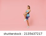 Small photo of Full size young sporty athletic fitness trainer woman wear blue tracksuit spend time in home gym train do stretch legs exercise isolated on pastel plain light pink background. Workout sport concept
