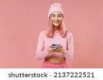Small photo of Young happy woman with bright dyed rose hair in rosy top shirt hat hold in hand use mobile cell phone isolated on plain light pastel pink background studio portrait. People lifestyle fashion concept.