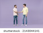 Small photo of Full size length two young smiling happy men friends together in casual t-shirt meeting together greeting hold hands folded handshake gesture isolated on purple background studio Tattoo translate fun