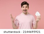 Small photo of Sick ill ailing allergic man has red eyes runny nose suffer from allergy hold paper napkin isolated on pastel pink color wall background studio Healthy lifestyle disease treatment cold season concept